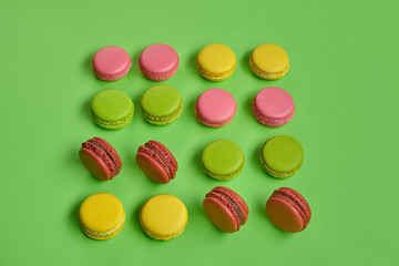 Colored macaron or macaroon, sweet meringue-based confection on green background. Close-up, copy space.
