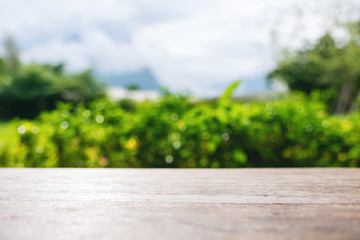 Closeup image of a vintage wooden table with blur green nature background