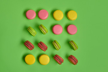 Colored macaron or macaroon, sweet meringue-based confection on green background. Close-up, copy space.
