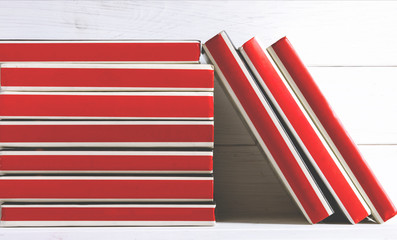 Many red-bound books stand on a white wooden shelf