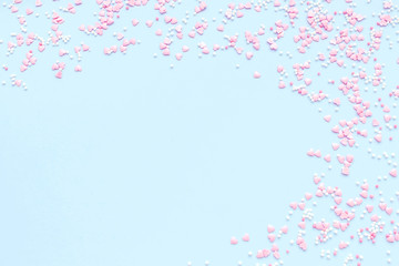 Festive romantic gentle abstract background for the design. Pink confetti in the shape of hearts on a blue background. Top view, flat lay composition. Copy space for text.	