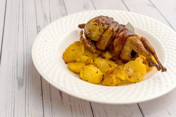 Roasted quail wrapped in bacon and sauteed potatoes