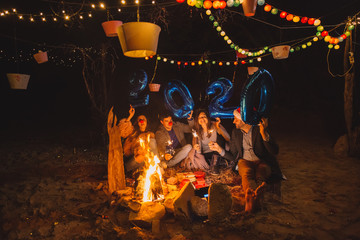 Happy friends holding 2020 blue balloons at New Year party, having fun together