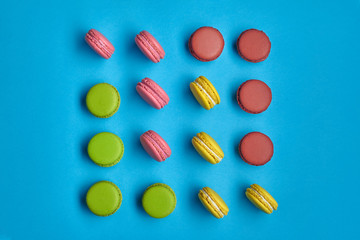 Colored macaron or macaroon, sweet meringue-based confection on blue background. Close-up, copy space.