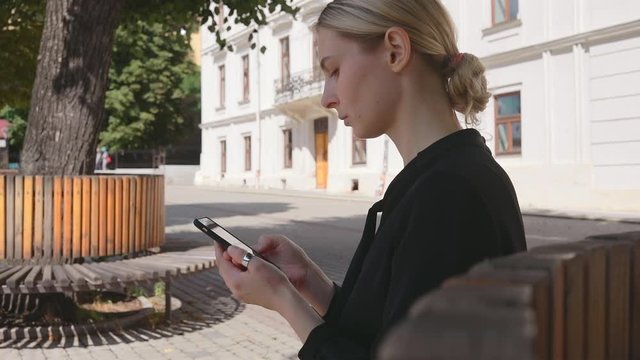 Pretty caucasian business woman sitting on old town square use smartphone in social internet media 5g technology