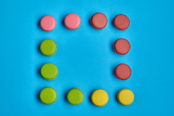 Colored macaron or macaroon, sweet meringue-based confection on blue background. Close-up, copy space.