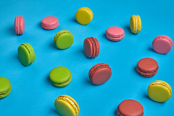Fototapeta na wymiar Colored macaron or macaroon, sweet meringue-based confection on blue background. Close-up, copy space.