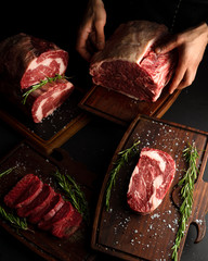 Butcher showing different cuts of raw meat. Low key image, vertical orientation.