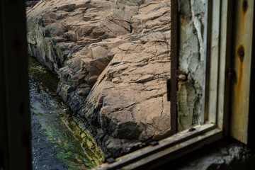 Abstract image of a big rock formation on the Black Sea shore seen through a broken window.