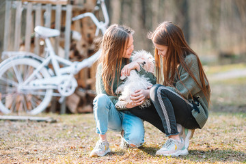 Fototapeta premium Little girls with a white puppy. A puppy in the hands of a girls