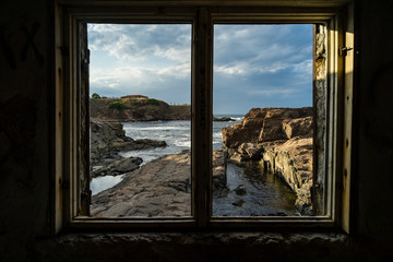 Window in an abandoned concrete structure towards the rocky coastline of the Black Sea 