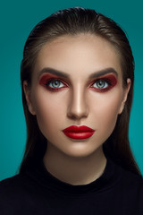 Close-up glamour portrait of a beautiful model with bright make-up posing over a gray background.