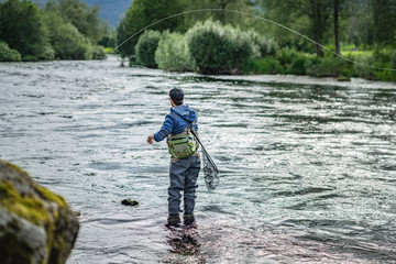 Angler mit Angel in Wathose im Wasser beim Fliegenfischen