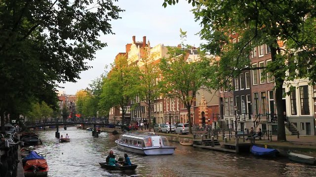 classical and traditional view of Amsterdam canals at summer time with boats and old architecture of the capital of the Netherlands