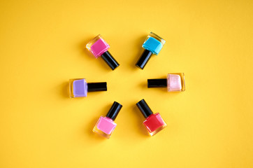 Color nail polish bottles on yellow background composition.