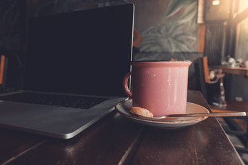 Nómada digital trabajando en una cafetería con su ordenador y un café 