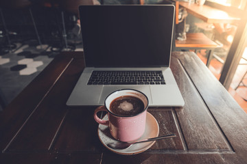 Nómada digital trabajando en una cafetería con su ordenador y un café 