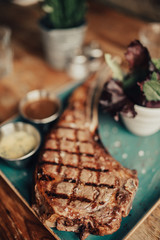 A close up shot of a beef steak served on the green plate with salad and sauces. Concept of restaurant, food and culinary.