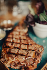 A close up shot of a beef steak served on the green plate with salad and sauces. Concept of restaurant, food and culinary.