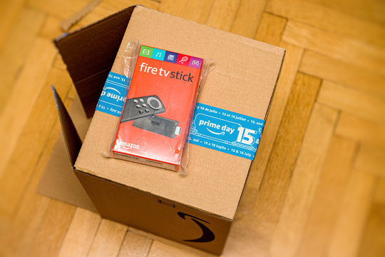 Paris, France - Jul 15, 2019: unboxing new Amazon Fire TV Stick with Alexa Remote a digital media player streaming device and its microconsole remote developed by Amazon - wooden floor background