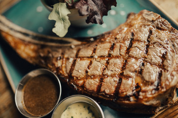 A close up shot of a beef steak served on the green plate with salad and sauces. Concept of restaurant, food and culinary.