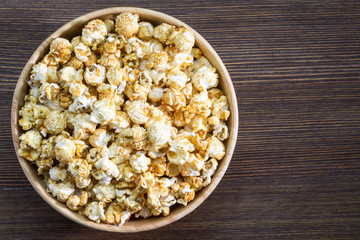 Corn popcorn in bowl on wooden background