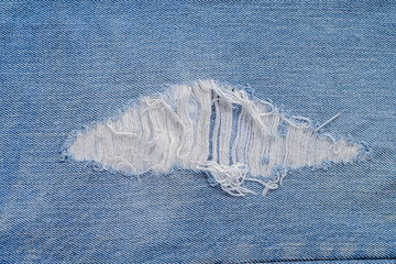 tear of denim texture with a hole and threads showing