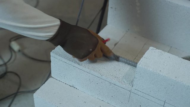 builder hands marking aerated concrete block with pencil and steel armature bar