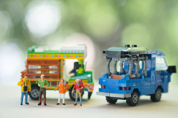Fototapeta na wymiar Miniature people : Traveller backpacker standing with Thai farming trucks and Thai style taxi.