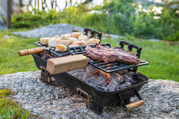 Steak and Scallops grilling on a hibachi as hot charcoal develops smoke and flames on a summer night