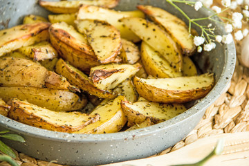 Oven baked potato in the oven with peel and spices in a baking dish. View from above. Potato wedges in peel, homemade lunch concept, dish with potatoes, baked potato recipe, Rustic potato