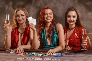 Fototapeta premium Group of a young wealthy ladies are playing poker at a casino.