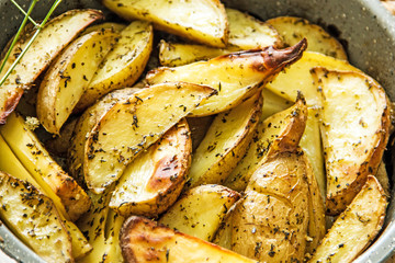 Oven baked potato in the oven with peel and spices in a baking dish. View from above. Potato wedges in peel, homemade lunch concept, dish with potatoes, baked potato recipe, Rustic potato