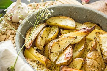 Oven baked potato in the oven with peel and spices in a baking dish. View from above. Potato wedges in peel, homemade lunch concept, dish with potatoes, baked potato recipe, Rustic potato