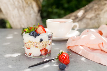 Oatmeal with yogurt with strawberries and blueberries with spoon and cup of tea
