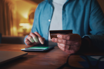 Close-up of man using credit card for paying on smart phone