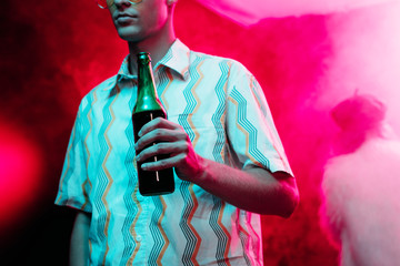 Cropped view of man with bottle of alcohol during rave in nightclub