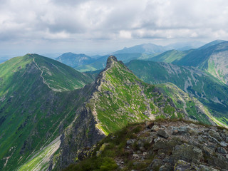 view from Ostry Rohac peak on Western Tatra mountains or Rohace panorama. Sharp green mountain peak placlive with hiking trail on ridge. Summer blue sky white clouds. - obrazy, fototapety, plakaty