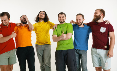 Young men weared in LGBT flag colors isolated on white background. Caucasian male models in shirts of red, orange, yellow, green, blue and purple. LGBT pride, human rights, choice concept. Look happy.