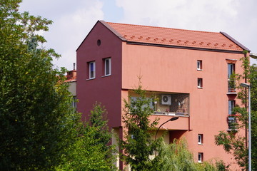 small triangular balcony in the house with a coral facade and potted flowers on fence. a place to...