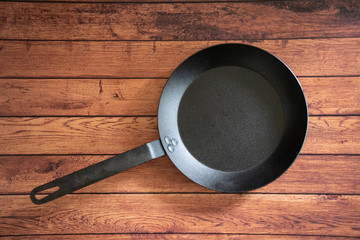 Isolate carbon steel skillet pan on a wooden background - overhead top view
