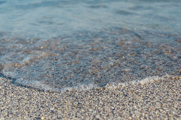 Closeup of sandy beach with soft incoming waves. Selective focus