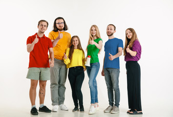 Obraz premium Young man and woman weared in LGBT flag colors on white background. Caucasian models in bright shirts. Look happy together, smiling and hugging. LGBT pride, human rights and choice concept.