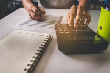 Hand man doing finances and calculate on desk about cost at office. 
