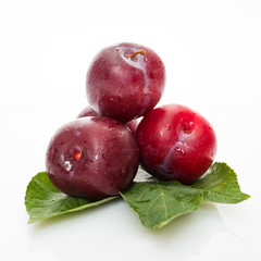red  plum with green leaves isolated on white background