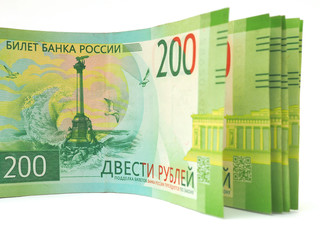 A pack of Russian bills of two hundred rubles is on a white surface. The banknote depicts a...