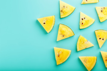 Pattern of slices of fresh yellow watermelon on a blue background. View from above. Free space