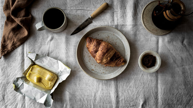 Breakfast scene with coffee, croissant and butter on the table