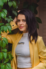 Beautiful young girl among the greens in stylish and classic yellow suit. Portrait. Fashion.