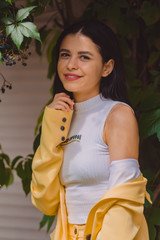 Beautiful young girl among the greens in stylish and classic yellow suit. Portrait. Fashion.